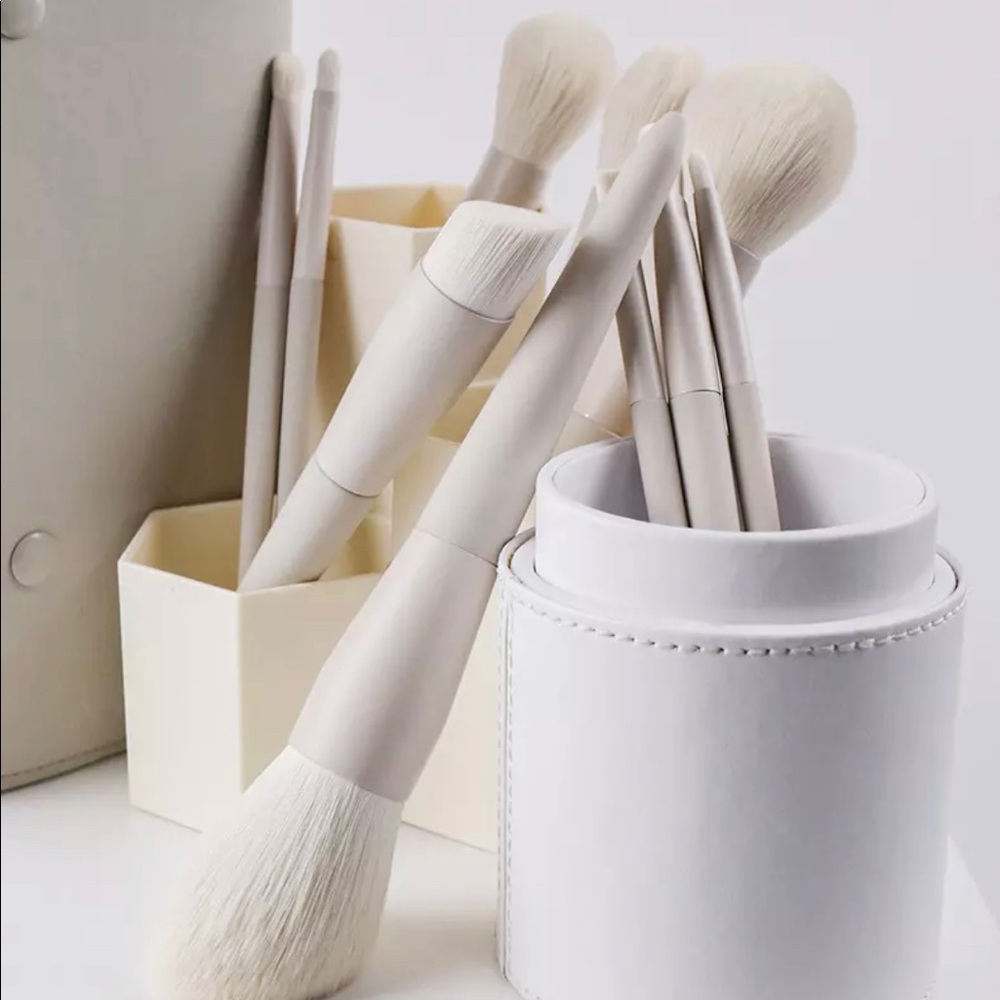 White and greige goat hair face and eye makeup brushes with a weighted handle.